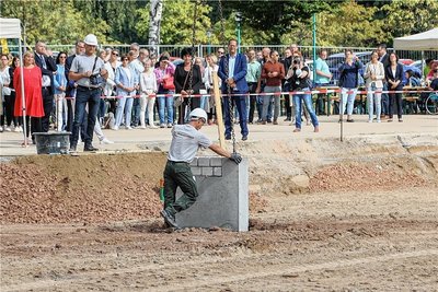 Der Grundstein für die neue Therapieeinrichtung für Kinder und Jugendliche wird mit einer Zeitkapsel im Inneren in den Boden eingelassen. 