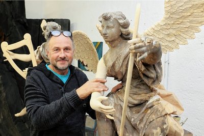 Mit einem Engel auf Tuchfühlung: Holzbildhauer Peter-Paul Brockhage an einer restaurierten Figur aus Wengelsdorf. Nach der Farbgebung werden sich alte und neue Teile nicht mehr voneinander abheben. 