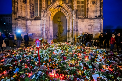 Zahlreiche Blumen und Kerzen liegen nahe dem Weihnachtsmarkt vor der Johanniskirche in Gedenken an die Opfer.