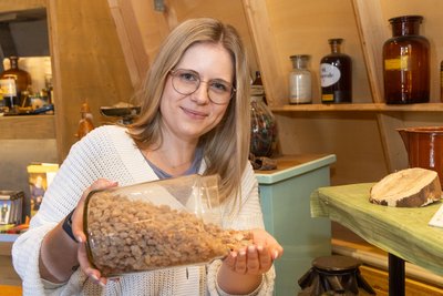 Beatrix Nowarra zeigt Weihrauch. Er ist ein Rohstoff. In Sorge um Lieferketten wurde diesmal der doppelte Jahresbedarf bestellt. Im Hintergrund ist das Museum am Räucherkerzenland zu sehen.