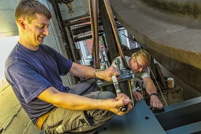 Als eine "Riesenaktion" bezeichnen die Haustechniker auch die Umstellung des Antriebs der Dampfmaschine im Jahr 2015. Im Bild schrauben Heiko Vieweger (links) und Andreas Quitschau an den Schwungplatten für den Motor. 