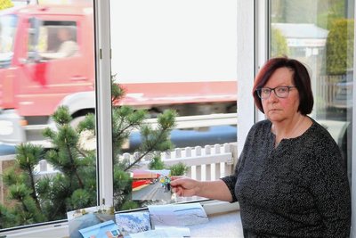 Gisela Kahlert zeigt an ihrem offenen Fenster Bilder, wie Lkw an Kindern vorbeifahren. 