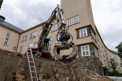 Eine massive Betonstützwand hat Baggerfahrer Aaron Döbel von der Pöhla Bau GmbH freigelegt. Mit der 100-jährigen Mauer hinter der Treppe hatte keiner gerechnet. Sie wird nun nicht abgepickert, sondern wird im Bauwerk belassen.