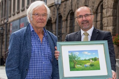 Michael Sowa übergibt an Kulturbürgermeister Steffen Zenner (CDU) das fertig gestellte Bild, das er mit dem Eintrag in das Goldene Buch der Stadt begonnen hatte. Vater und Sohn laufen auf eine im Teich stehende Frau zu: "Mutti!"