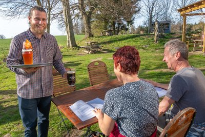 Robin Reinsch serviert im Biergarten der Bergschänke Getränke.