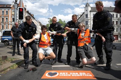 Für die einen ist es Protest, für die anderen Nötigung: Polizeibeamte heben Anfang Juli zwei Klimaaktivisten der Gruppe "Letzte Generation" von einer Straße in Leipzig.