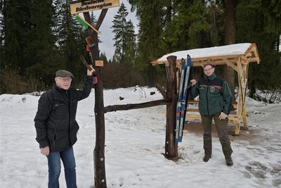 Gottfried Fuchs vom Verein Historische Skitruhe Schönheide (l.), der die Skier zur Dekoration bereitgestellt hat, und Revierförster Alexander Clauß auf dem erweiterten Parkplatz an der Loipe.