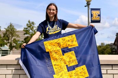 Hannah Teubel hält vor der „Everett High School“ eine Flagge mit dem Logo dieser - zehn Monate war sie eine Schülerin an der US-amerikanischen Schule.