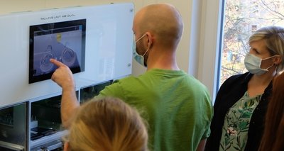 Zahntechniker Stephan Illgen erklärt den Auszubildenden und ihrer Lehrerin Adrienne Falcke die Funktionsweise einer computergesteuerten Fräs- und Schleifanlage. 