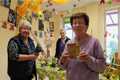 Karin Kunz (links) mit Motorrad-Frosch und Monika Kühn nutzen den Ostermarkt in der Tagespflege Johanngeorgenstadt. Doreen Otto (hinten) gehört zum Mitarbeiterteam. 