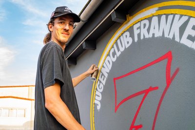 Philipp Kühn von Rebel Art übernahm es, das mit etwas Hilfe von KI gestaltete neue Logo für den „Club Seven“ auf die Fassade zu übertragen.