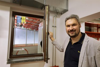 Fachbereichsleiter Stefan Aurich öffnet das Fenster in der neuen Kabine für die Gäste-Mannschaften, die nun direkt ins Stadion schauen.
