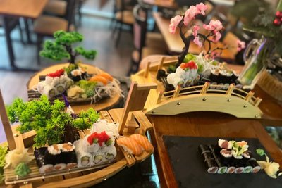 Ein Sushi-Menü für zwei Personen zum Preis von 44,90 Euro wird auf einem Holzschiff (vorn) oder auf weiteren Holzplatten und -brücken serviert.