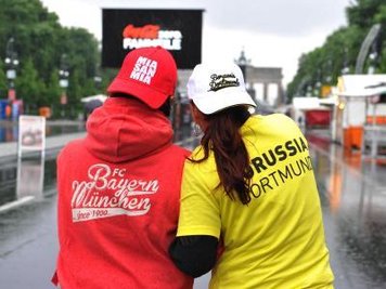 Zwei Frauen in Fankleidung auf der verregneten Fanmeile in Berlin.