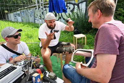 Jakob Heinzmann vom Kulturhauptstadt-Team, Künstler Martin Maleschka und Uwe Fretsch (von links). Uwe Fretsch gab Autoteile aus der Garage seines Vaters für das Kunstprojekt ab, darunter den Anlasser eines Wartburgs (Mitte).
