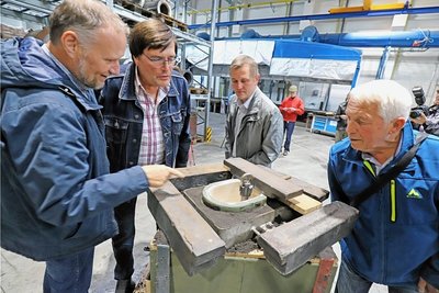 Ralph Gerlach, Bauamtsleiter der Gemeinde Halsbrücke (l.), erklärt vor dem Gussvorgang den Anwesenden die Idee der Glocke für die Gemeinde. 