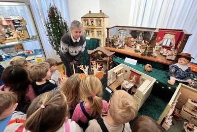 Vorschulkinder aus der Kita „Pfiffiküsse“ waren am Donnerstag die ersten Besucher. Museumsleiterin Martina Bundszus brachte ihnen die Puppenstuben und Puppenküchen näher.