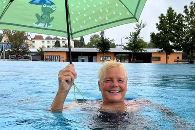 Gabriele Hoppe aus Rossau zog am Montag im Freibad Mittweida gut gelaunt ihre Bahnen. Der Regen störte sie nicht, den Schirm nahm sie aus Spaß in die Hand.