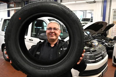 Werkstatt-Meister Michael Quaas mit einem Winterreifen im VW-Autohaus Werner in Mittweida.