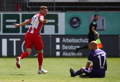 Heidenheims Konstantin Kerschbaumer bejubelt sein Tor zum 2:0. Aues Aues Philipp Riese sitzt am Boden.