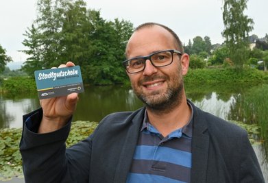 Innenstadtmanager Stefan Herold mit einem Stollberger Stadtgutschein im Scheckkartenformat. 