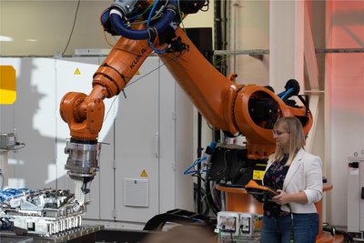 Die wissenschaftliche Mitarbeiterin Antje Ahrens zeigt an der Roboteranlage REAL-M, wie ein flaches Blech umgeformt wird.
