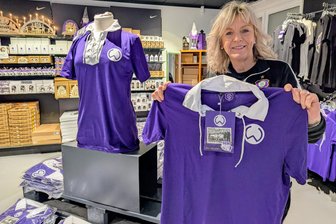 80 Jahre Erzgebirge Aue: Zwei Jubiläen in 2026 – Fans des FCE kleiden sich passend ein - Fanshop-Chefin Simone Adler mit dem neuen Retro-Sondertrikot.