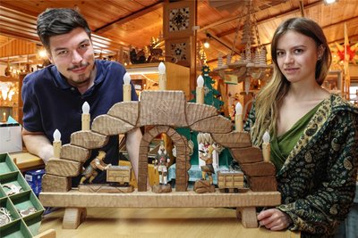 Schnitzkunst aus dem Erzgebirge: Lukas Vogel und Sophie Zacher mit einem Schwibbogen, der nach Kundenwunsch gestaltet wurde.