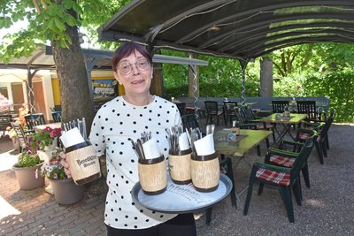 Sibylle Müller deckt in Braunsdorf den idyllischen Biergarten der Gaststätte „Am Bahnhof“ ein.