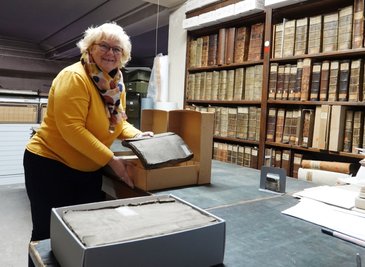 Die Leiterin des Stadtarchivs Silva Teichert hat sich ersten Archivkartons mit historischen Unterlagen vorgenommen. Die Bestände werden vor dem Umzug auf Vollständigkeit, Zustand und Schäden geprüft. 