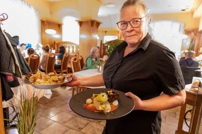 Chefin Sandra Mann serviert einen großen Garnelentopf (hinterer Teller) und Lachsfilet.