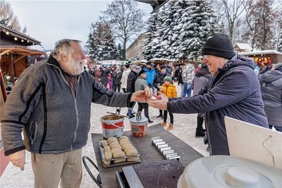 Natürlich dürfen auf einem Weihnachtsmarkt Dinge wie Glühwein und Bratwurst nicht fehlen. Giso Lorenz (links) aus Lugau verkauft in Geyer an einer 34 Jahre alten umgebauten Feuerwehr Bratwurst, Schaschlik und Knacker, hier bedient er Günther Bachmann aus Rudolstadt in Thüringen, der Urlaub im Erzgebirge macht. 