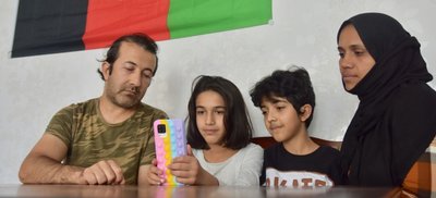 Assadullah (links) und Media Khaleqian (rechts) mit zwei ihrer insgesamt fünf Kinder, Ruhalla (Mitte rechts) und Fatima. Sie schauen sich täglich im Internet Nachrichten und Videos über den Zustand ihres Heimatlandes an, seitdem die Taliban dort die Macht ergriffen haben. 