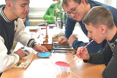 Achtklässler Etienne, Physikfachlehrer Martin Weinke und Achtklässler Mohammad (v. r.) bereiteten Spider Race für die Grundschüler vor.