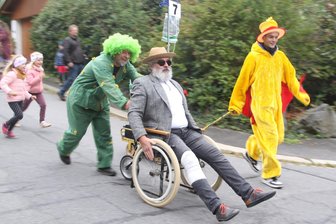 80er-Jahre Trainingsanzüge, ein falscher Bart und ein Roboterhund beim Tante-Ella-Kofferlauf in Augustusburg - Unter erschwerten Bedingungen fuhren die Mitglieder des Augustusburger Carnevalsclubs durch das Waldvillenviertel.