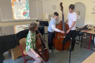 Der 13-jährige Vilen Gering darf die Saiten am Kontrabass von Leopold Rucker zupfen. Auch Cellistin Julia Flögel lässt Schüler ihr Instrument ausprobieren.