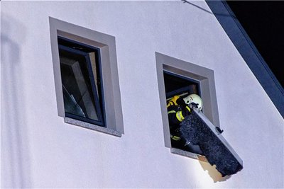 Ein Feuerwehrmann wirft Möbelteile zum Ablöschen aus dem Fenster.