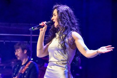 Selina Tulasoglu in einem atemberaubendem cremefarbenen Kleid zum Titel „Let's Get Loud“.