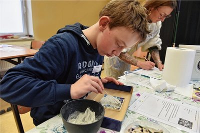 Die Schüler der 7. Klassen testen sich in sechs verschiedenen Aufgaben, mit denen ihre Fähigkeiten gecheckt werden. Richard Niebisch hat auf einer Fliese kleine Mosaiksteine verlegt und verschließt mit Mörtel die Fugen.