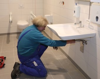 Gerd Meier von der Firma Gebäudetechnik aus Beierfeld bei der Installation des Waschbeckens in der barrierefreien Toilette.