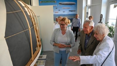 Die Urenkel der wichtigsten deutschen Luftschiffpioniere des 19. Jahrhunderts treffen sich: Eva Weber (rechts), Nachfahrin von Georg Baumgarten, und Günter O. Schulz, Nachfahre von Hermann Wölfert, haben sich gemeinsam mit Silvia Slazenger, Tochter Eva Webers, die Gedenkausstellung in Grüna mit Luftschiffmodell angesehen. 
