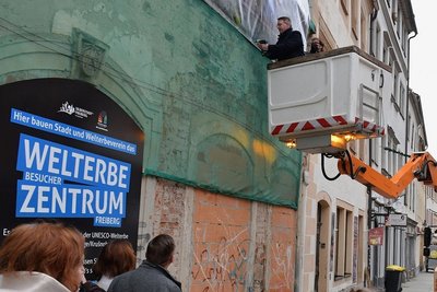 Ein Werbebanner kündet in der Petersstraße vom künftigen Welterbezentrum. Freibergs Oberbürgermeister Sven Krüger brachte am Dienstag symbolisch die letzte Schraube an. 