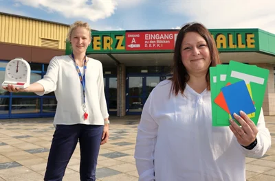 Antje Pflug (links) und Julia Krauße vom HC Glauchau/Meerane präsentieren vor einem Heimspiel des Handball-Zweitligisten EHV Aue die Utensilien des Kampfgerichts vor der Erzgebirgshalle. 