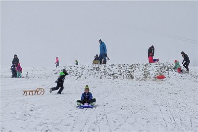 Die ersten Kinder rodeln am Fuße des Skihangs. 