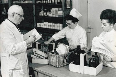 Hanna Gotter (Mitte) 1963 als junge Schwester bei der Medikamentenausgabe. Sie trägt eine Siebenfaltenhaube. Links im Bild Klinik-Apotheker Walter Wetzig.