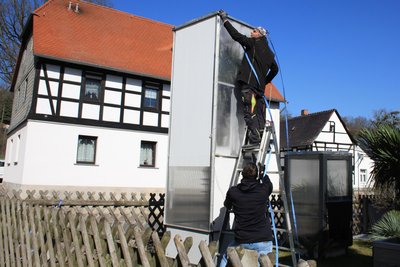 Zusammen mit einem Helfer baut Jens Fechner (oben) die Einhausungen der Palmen in seinem Garten ab.