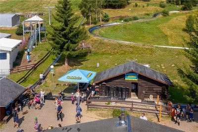 Zu beliebten Ausflugszielen in Oberwiesenthal gehören die Sommerrodelbahn (vorn) und die "Fly-Line" (links oben), bei der sich Besucher mit einem Sicherheitsgurt in eine Art Fahrbahn einhängen, auf der sie in luftiger Höhe ins Tal sausen.