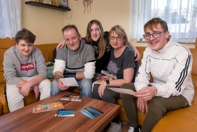 Jamie-Niklas, Vater Torsten, Alea-Elaine, Mutter Yvette und Collin Leister (von links) schauen sich auf der heimischen Couch ausgedruckte Bilder aus der Zeit des Reha-Aufenthaltes an. 