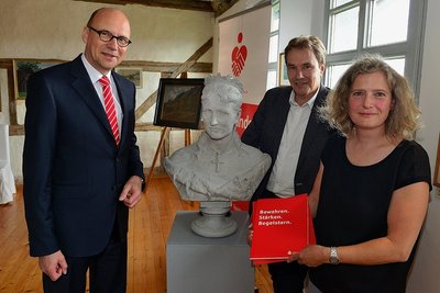 Museumsleiterin Sibylle Karsch, Sparkassenchef Hans-Ferdinand Schramm (l.) und Oberbürgermeister Ralf Schreiber mit der restaurierten Schilling-Büste von Königin Carola und dem Fördermittelbescheid.