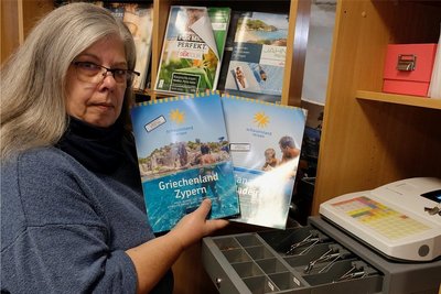 Silke Baumann mit neuen Urlaubskatalogen und leerer Kasse in ihrem geschlossenen Reisebüro.
